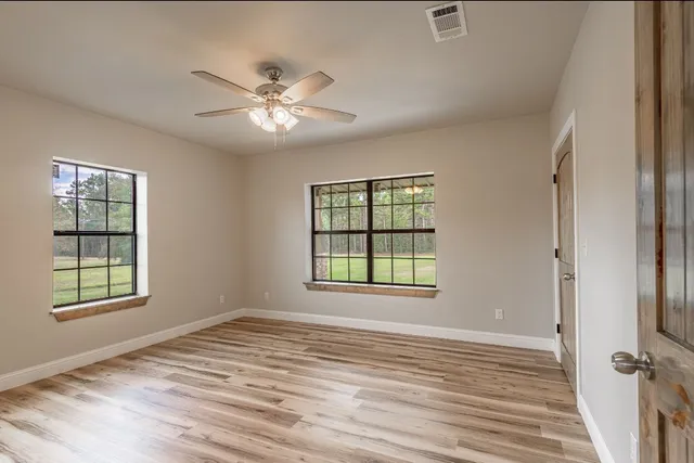 a view of an empty room with a window and wooden floor