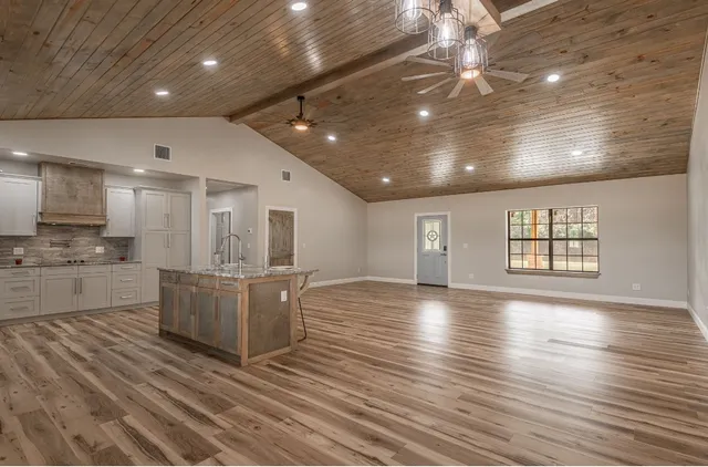 a large white kitchen with kitchen island a sink stainless steel appliances and cabinets