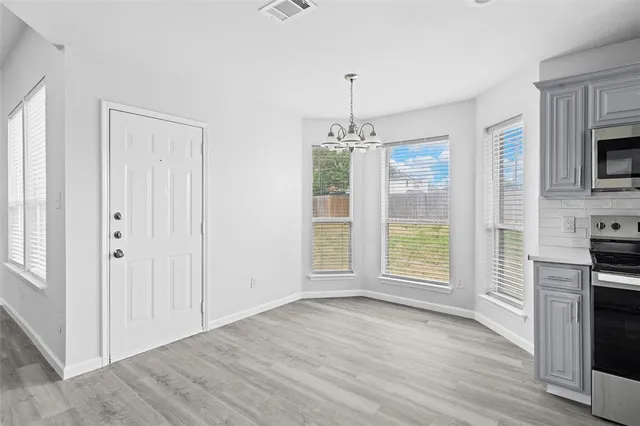 an empty room with wooden floor fireplace and windows