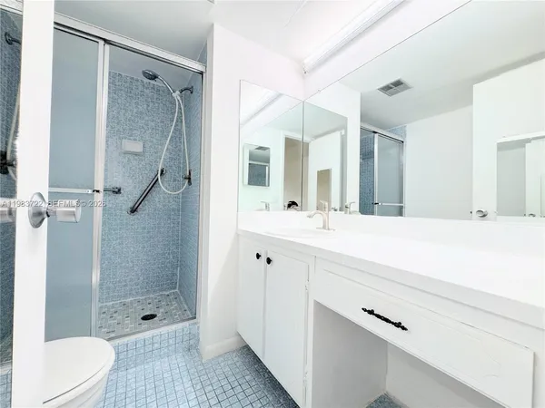 a bathroom with a shower sink vanity mirror and toilet