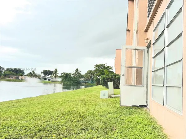 a view of a lake with a big yard and large tree