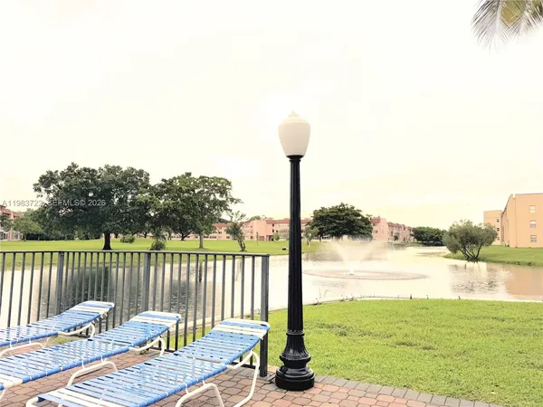 a view of a swimming pool with a dining table chairs in front of it