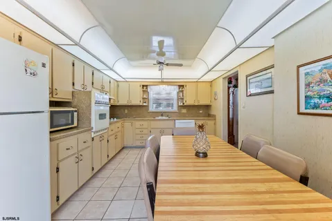 a large white kitchen with granite countertop a refrigerator a stove a sink dishwasher and white cabinets with wooden floor