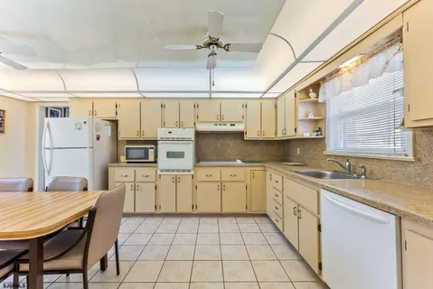 a kitchen with stainless steel appliances granite countertop a sink a stove a refrigerator cabinets and chairs