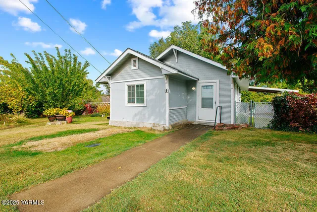 a front view of house with yard and trees in the background