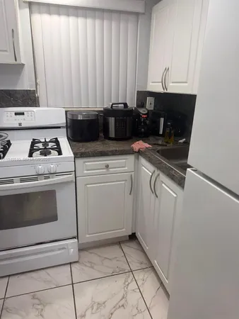 a kitchen with granite countertop white cabinets and white appliances