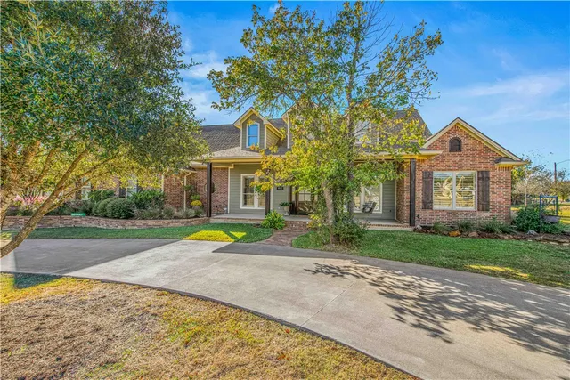 a view of a house with a yard and large tree
