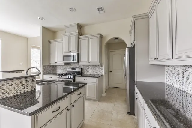 a kitchen with granite countertop a sink stove and cabinets