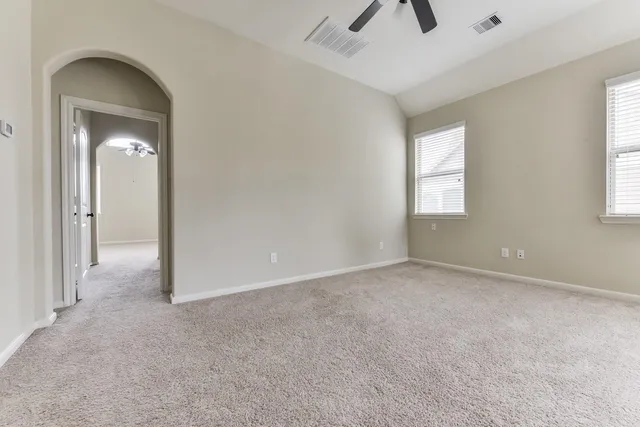 an empty room with chandelier fan and windows