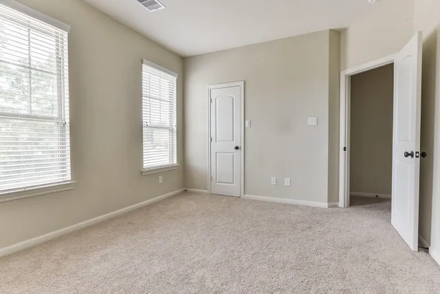 a view of an empty room with windows and closet area