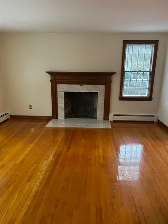 an empty room with wooden floor fireplace and windows