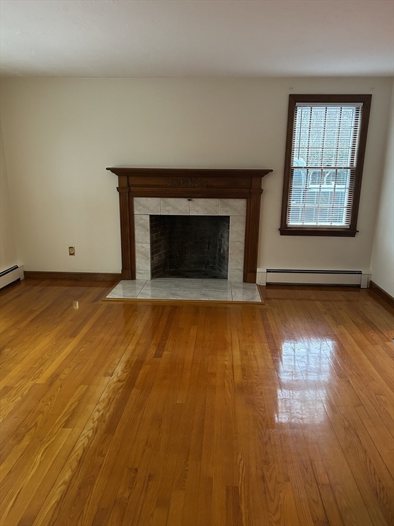 200 Plympton Road, Unit 200 Plymouth, MA 02360 - Photo 6 of 10 an empty room with wooden floor fireplace and windows