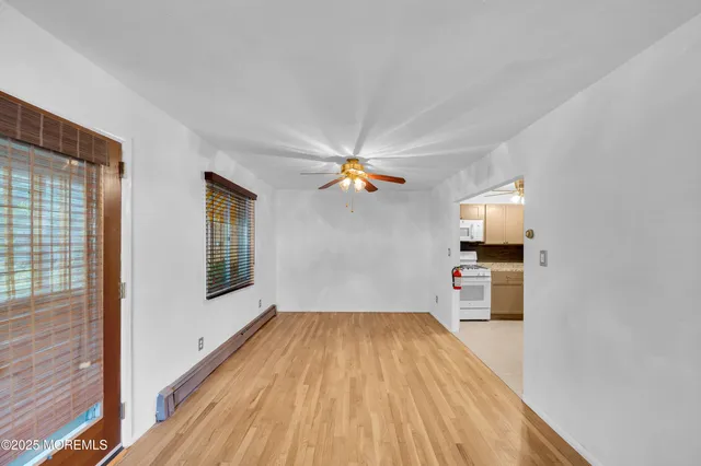 a view of a room with wooden floor a ceiling fan and windows