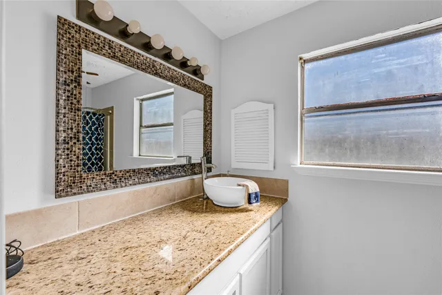 a bathroom with a granite countertop sink and a mirror