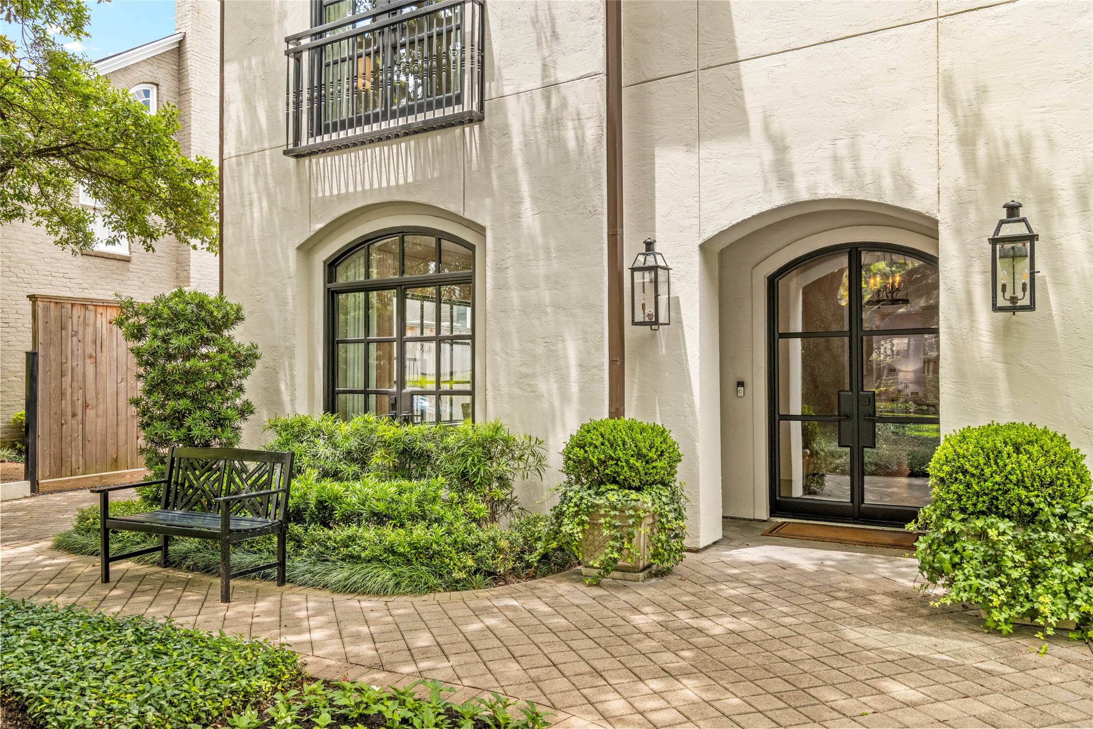 2216 Stanmore Drive Houston, TX 77019 - Photo 2 of 46 Arched steel-and-glass doors, lantern lighting, and manicured greenery create an inviting entry framed by classic architectural detail and a charming front sitting area.
