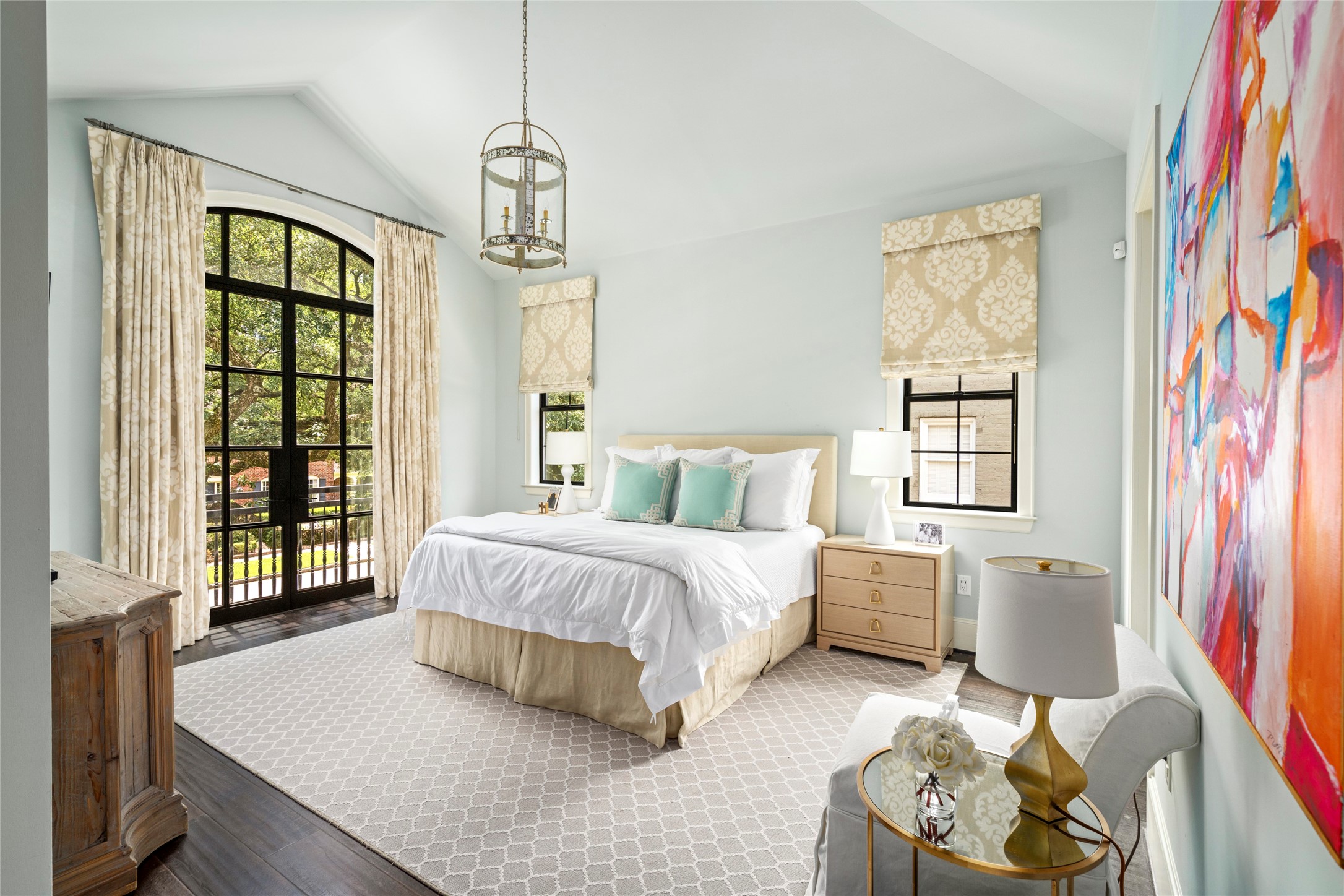 2216 Stanmore Drive Houston, TX 77019 - Photo 25 of 46 Upstairs primary suite with vaulted ceiling, arched steel doors, private balcony access, and soft natural light overlooking the tree canopy.