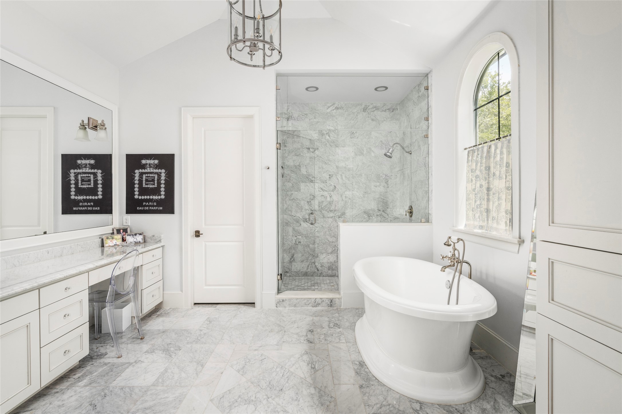 2216 Stanmore Drive Houston, TX 77019 - Photo 30 of 46 Elegant bath featuring marble flooring, a freestanding soaking tub, glass-enclosed shower, arched window, and refined polished fixtures.