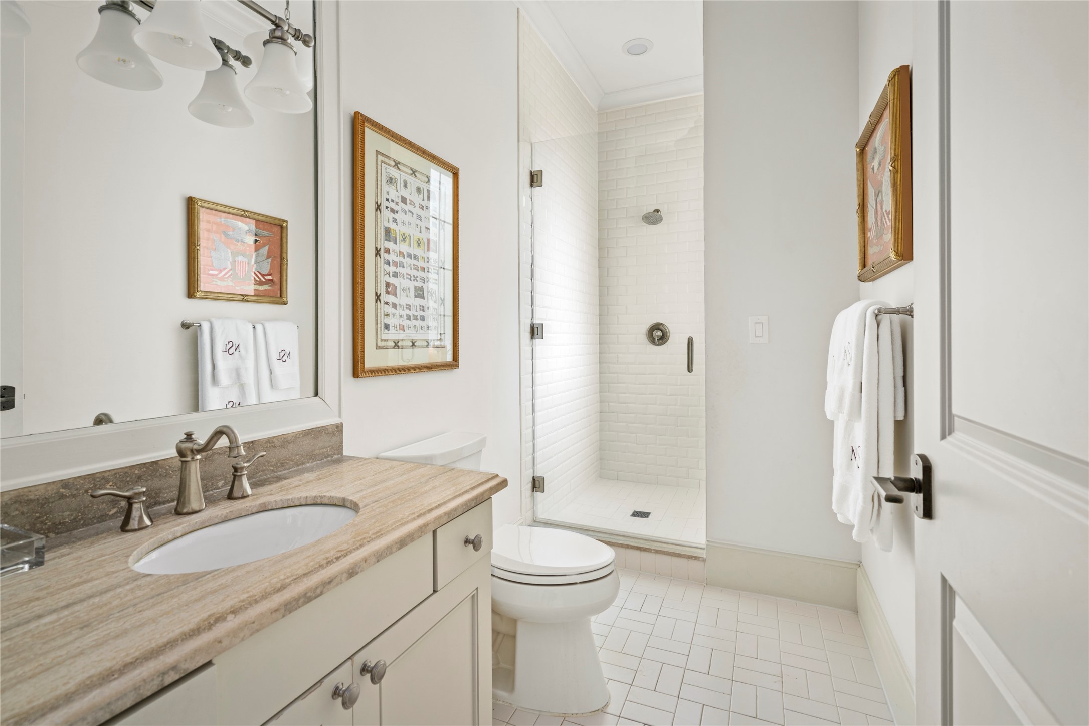 2216 Stanmore Drive Houston, TX 77019 - Photo 36 of 46 Private en-suite bath with a stone vanity, polished fixtures, and a glass-enclosed shower with classic white tile.