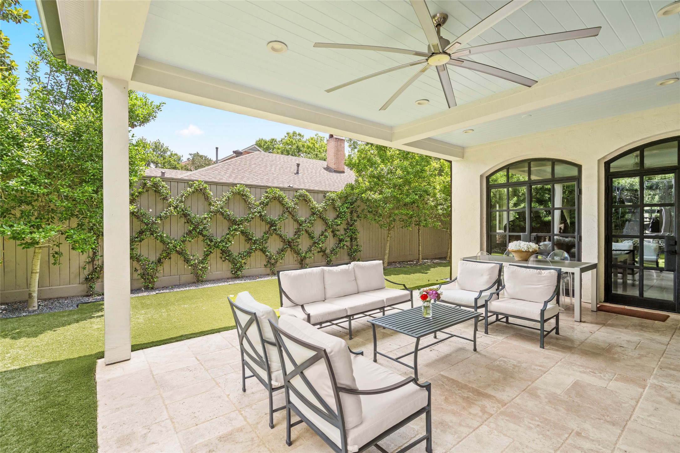 2216 Stanmore Drive Houston, TX 77019 - Photo 44 of 46 Covered seating area with ceiling fan and candlelight-style evening lighting, creating a warm and inviting outdoor setting after dark.