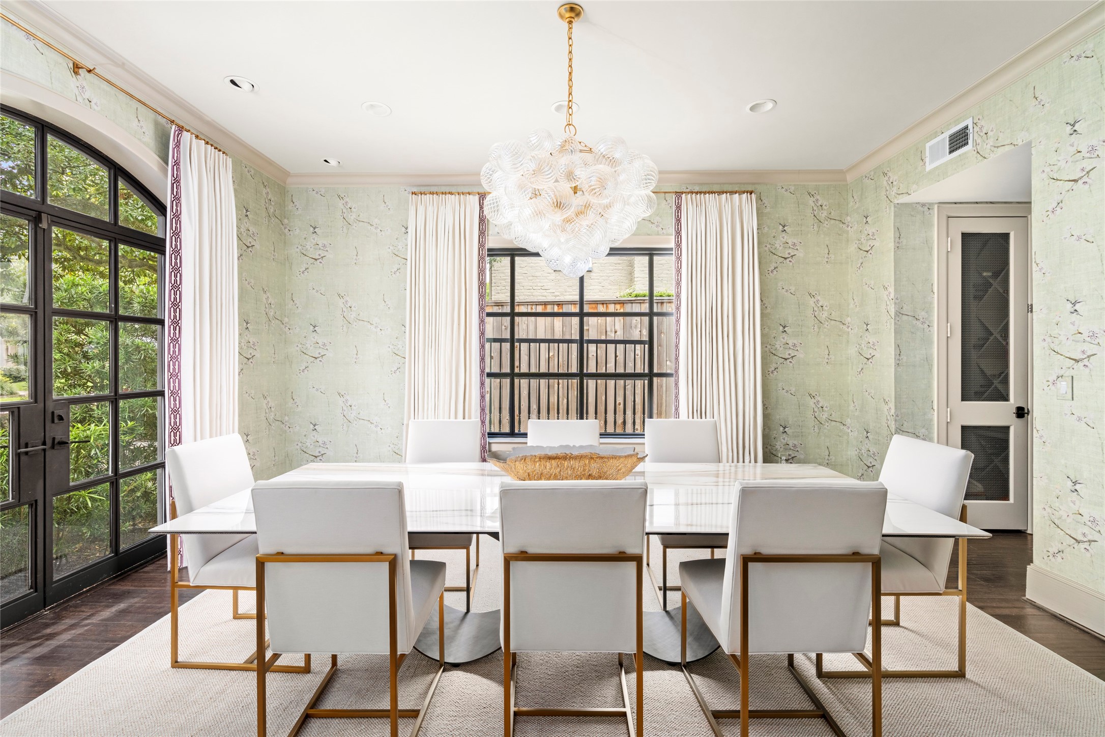 2216 Stanmore Drive Houston, TX 77019 - Photo 5 of 46 The formal dining room features garden-facing steel doors, tailored drapery, soft patterned wallcovering, and a sculptural chandelier that adds a refined focal point.