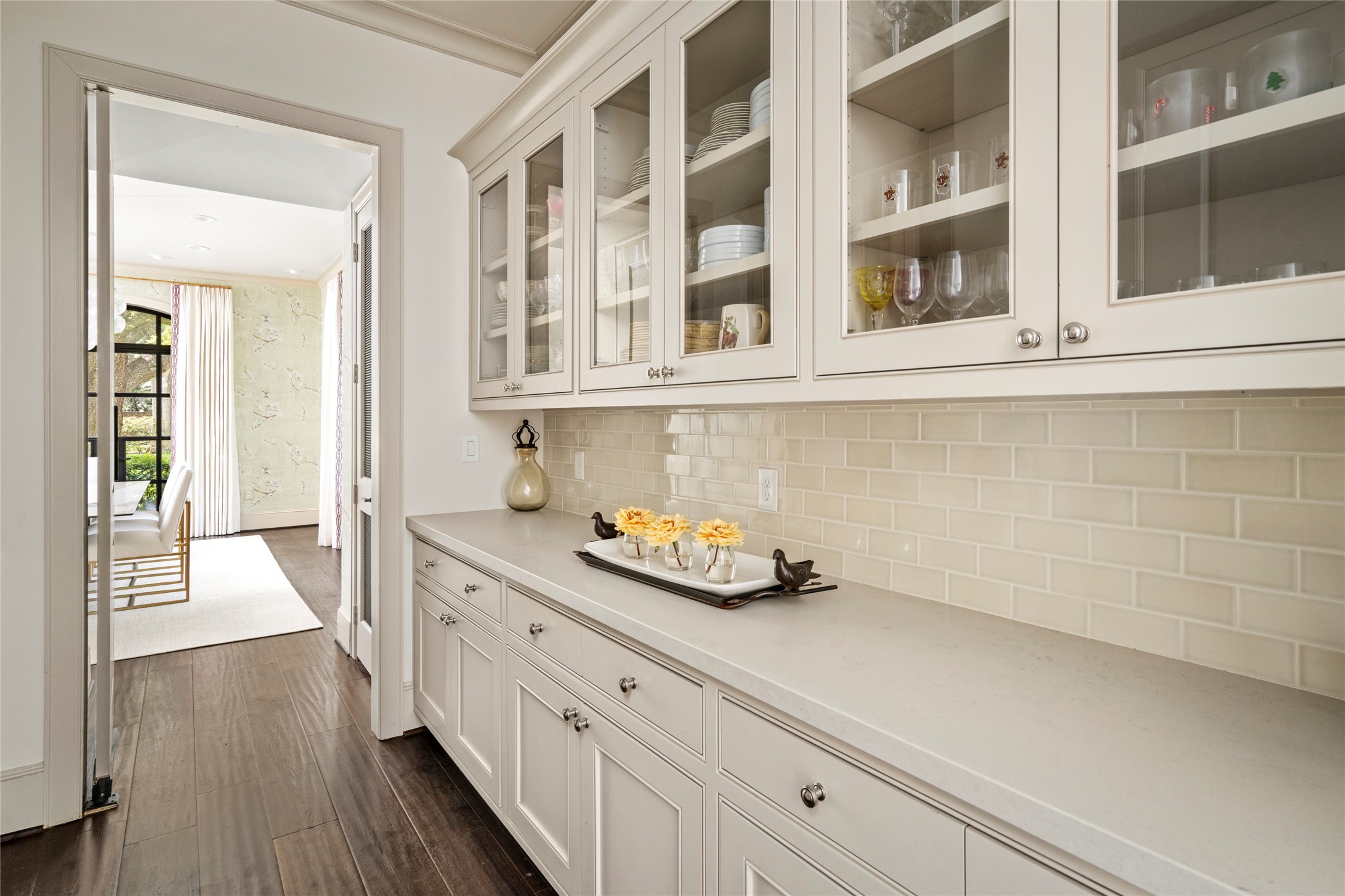 2216 Stanmore Drive Houston, TX 77019 - Photo 9 of 46 Elegant butler’s pantry with glass-front cabinetry, generous serving space, classic tile backsplash, and a seamless connection between the kitchen and formal dining room.