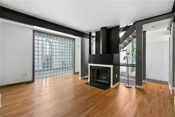 a view of an empty room with wooden floor fireplace and a window