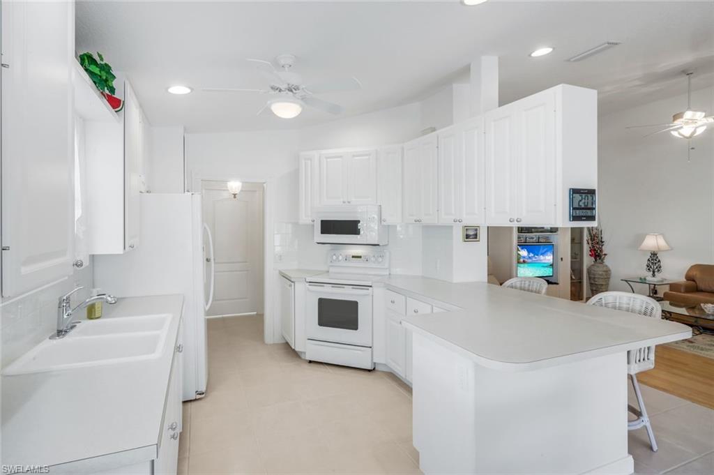 3609 Exuma Way Naples, FL 34119 - Photo 17 of 43 a kitchen with kitchen island a sink stainless steel appliances and white cabinets