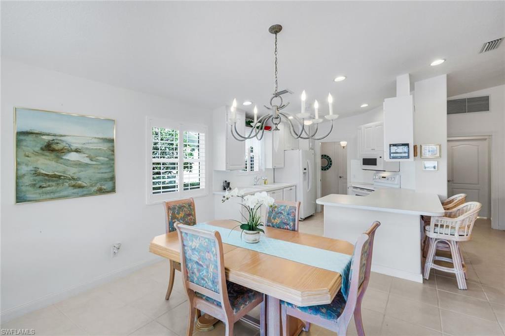3609 Exuma Way Naples, FL 34119 - Photo 20 of 43 a dining room with wooden floor a chandelier a wooden table and chairs