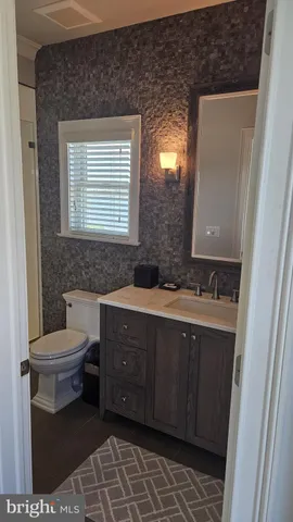 a bathroom with a granite countertop toilet sink and mirror