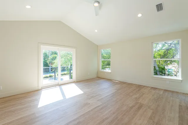 an empty room with wooden floor and windows