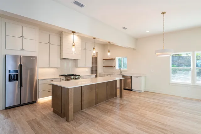 a kitchen with stainless steel appliances granite countertop a stove a sink dishwasher and a refrigerator with wooden floor