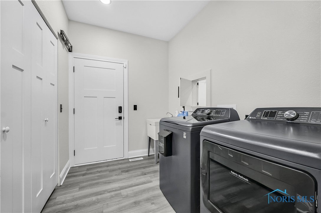 9414 Sheffield Road Perrysburg, OH 43551 - Photo 29 of 34 First floor laundry with pass through from the primary bedroom closet, a double closet, access to the garage, a deep sink and easy to maintain luxury vinyl flooring.