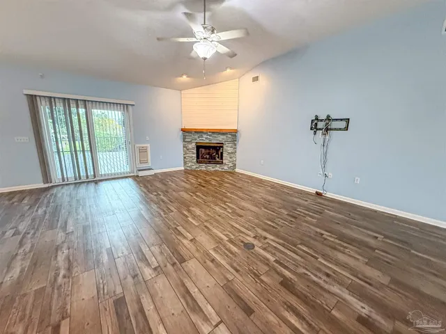 an empty room with wooden floor fan and windows