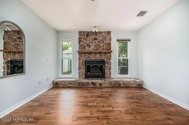 an empty room with windows fireplace and wooden floor