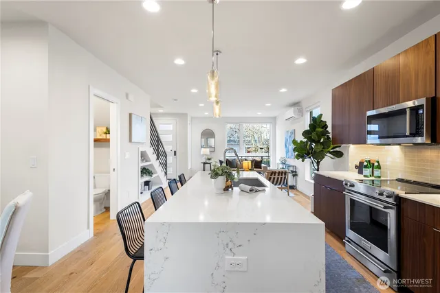 a kitchen with stainless steel appliances a table chairs in it and wooden floors