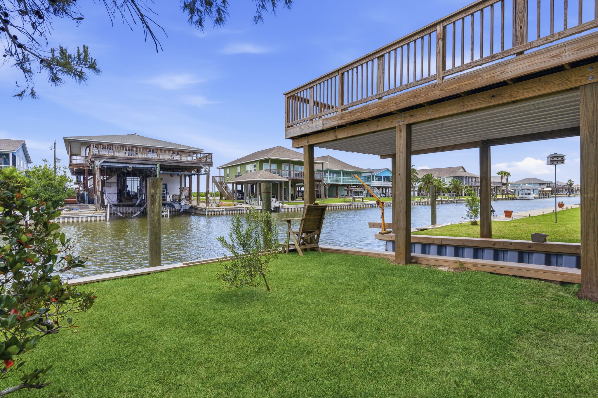 119 Sand Shoals Road Freeport, TX 77541 - Photo 14 of 34 Side yard along the canal — grass lawn down to the bulkhead, dock seating, and open canal views toward the bay.