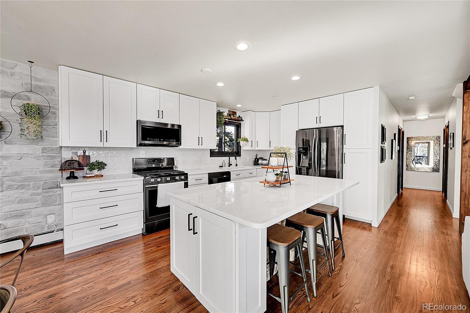 8959 South Hillview Road Morrison, CO 80465 - Photo 6 of 49 a kitchen with white cabinets and stainless steel appliances
