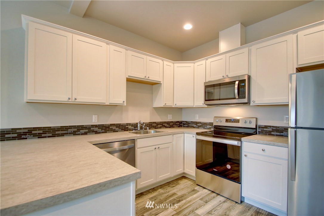 705 Peterson Road Burlington, WA 98233 - Photo 9 of 30 a kitchen with stainless steel appliances granite countertop white cabinets sink stove and microwave