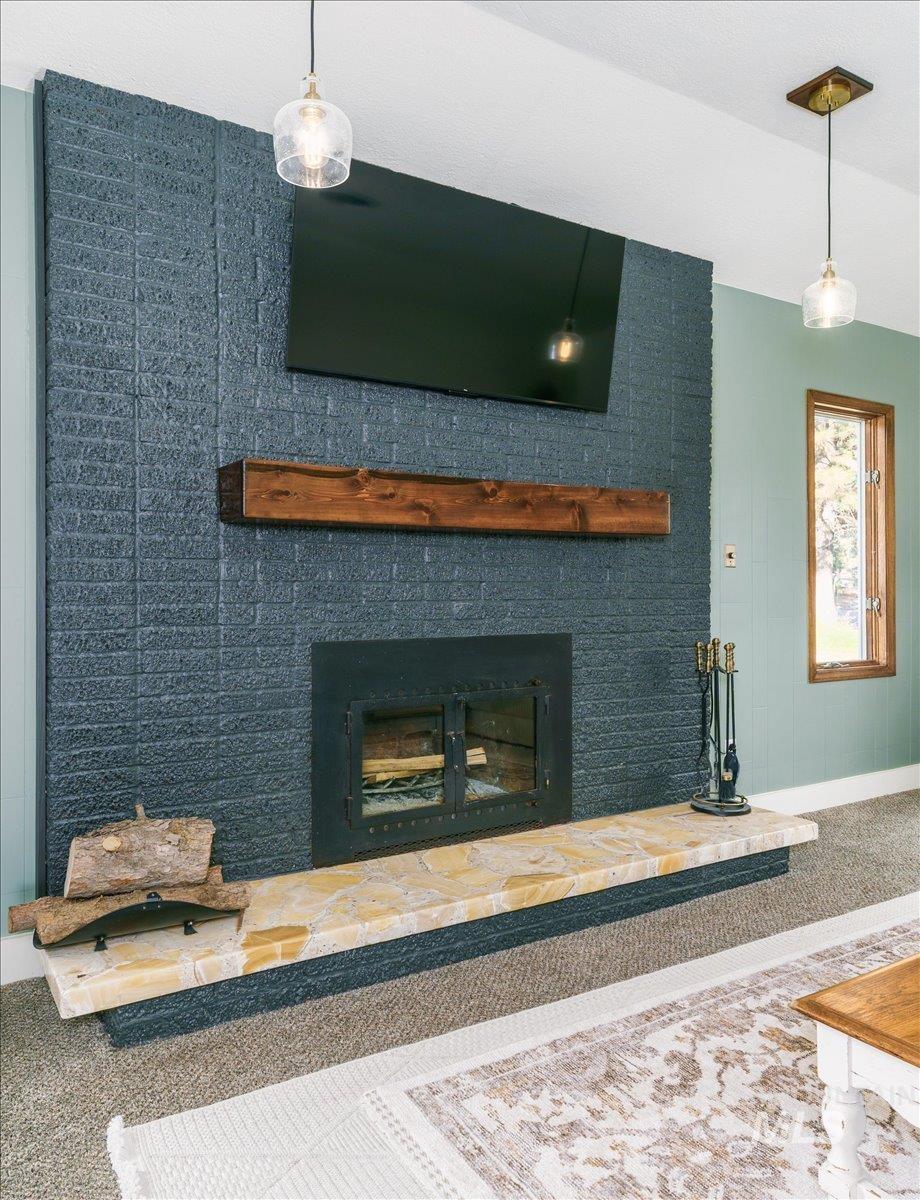 1401 Chokecherry Drive Pocatello, ID 83204 - Photo 5 of 46 Floor-to-ceiling brick fireplace surround in a dark hue, featuring a natural wood mantel and a stone hearth