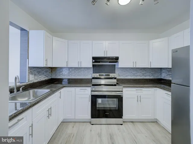 a kitchen with stainless steel appliances granite countertop a stove and white cabinets