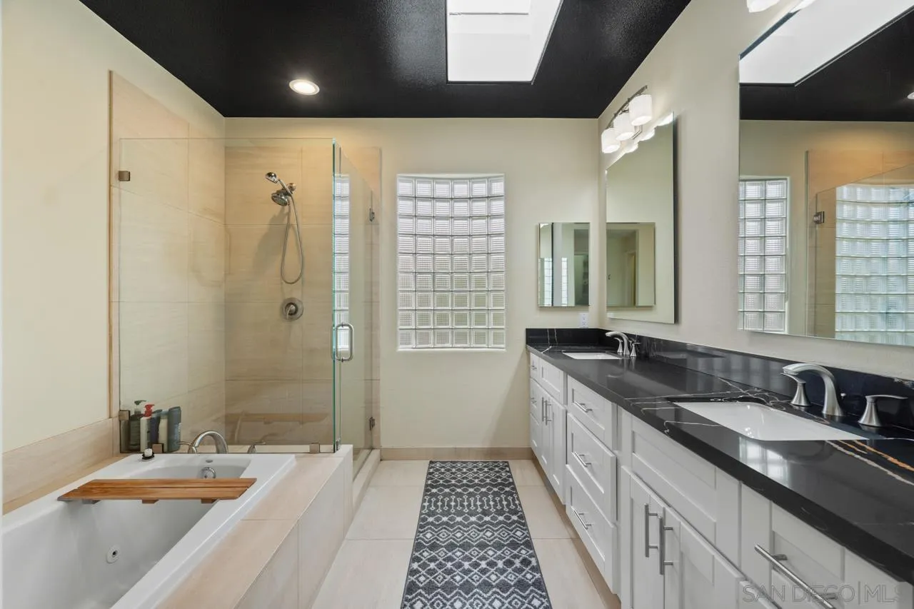 3128 Almahurst Row La Jolla, CA 92037 - Photo 14 of 21 a bathroom with a granite countertop double vanity sink a mirror and a shower