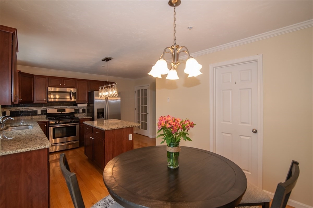 1975 Middlesex Street, Unit 51 Lowell, MA 01851 - Photo 12 of 34 a dining room with wooden floor a chandelier a wooden table and chairs