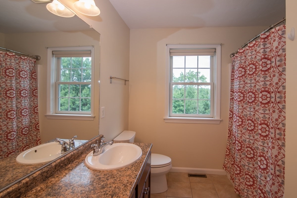 1975 Middlesex Street, Unit 51 Lowell, MA 01851 - Photo 17 of 34 a bathroom with a granite countertop sink toilet a large mirror and a window