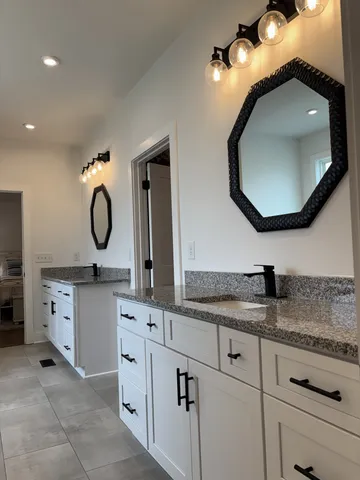 a bathroom with a granite countertop double vanity sink and a mirror