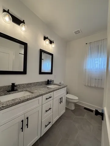 a bathroom with a granite countertop toilet sink and mirror