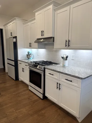 a kitchen with stainless steel appliances granite countertop a dining table chairs refrigerator sink and cabinets