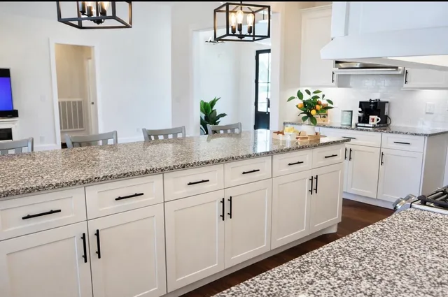a kitchen with granite countertop white cabinets and white appliances