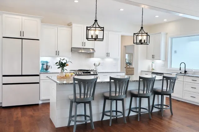 a kitchen with stainless steel appliances granite countertop a dining table chairs refrigerator sink and cabinets