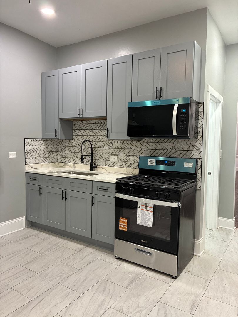 a kitchen with stainless steel appliances granite countertop a stove a sink and a microwave