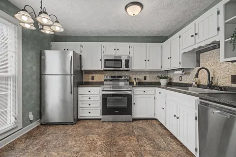 a kitchen with cabinets stainless steel appliances and a window